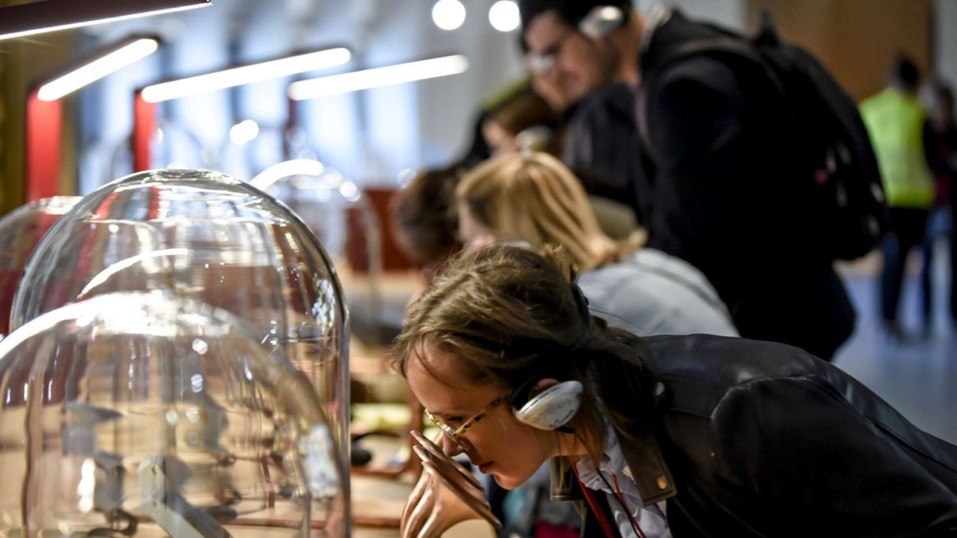Une jeune fille portant des lunettes observe une exposition interactive dans un musée ou centre scientifique à Bordeaux, avec d'autres visiteurs en arrière-plan.