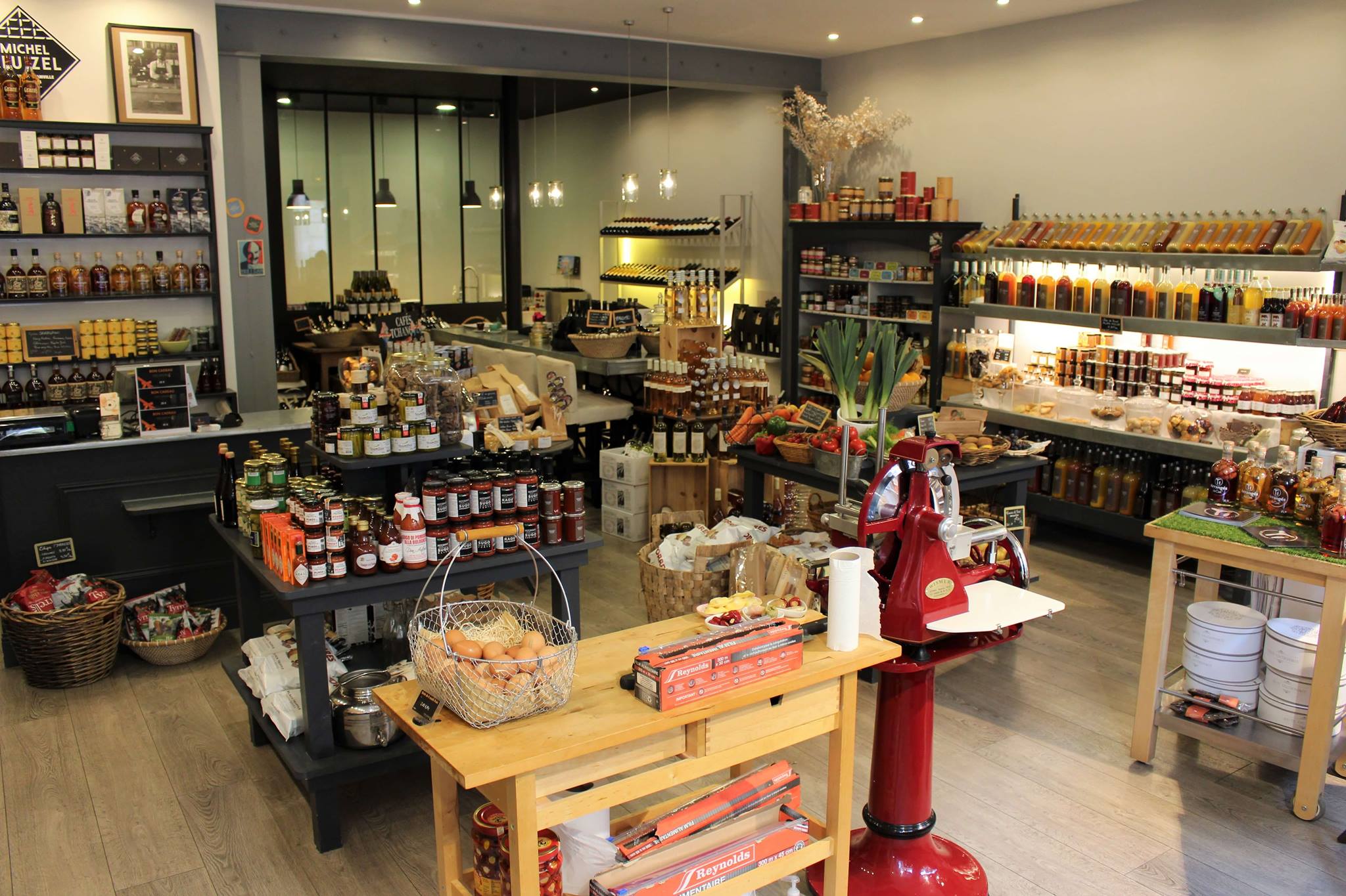 Intérieur d'une boutique bordelaise spécialisée dans les produits gastronomiques et les alcools, avec étagères remplies de bouteilles, bocaux et produits artisanaux, comptoirs en bois et une décoration chaleureuse.