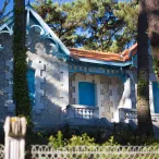 Petite chapelle blanche et bleue de style Art nouveau entourée de grands pins, avec détails architecturaux ornementaux et lierre grimpant, à Bordeaux.
