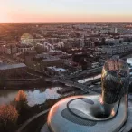 Vue aérienne au coucher de soleil des Bassins à flot de Bordeaux avec l'architecture moderne du Muséum d'Histoire Naturelle au premier plan, la Garonne et la ville en arrière-plan.