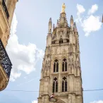La Tour Pey Berland, clocher gothique de la Cathédrale Saint-André de Bordeaux, vue depuis une rue étroite avec façades haussmanniennes de part et d'autre.