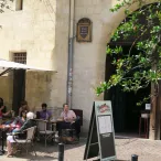 Terrasse extérieure du Cinéma Utopia à Bordeaux avec clients assis sous un parasol blanc, façade en pierre et végétation grimpante.