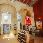 Intérieur du cinéma Utopia à Bordeaux, avec voûtes en pierre, murs rouges, affiches de films et mobilier en bois dans une ancienne chapelle.