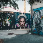 Fresque de street art à Bordeaux représentant un portrait d'homme barbu avec des éléments géométriques colorés, entourée d'autres graffitis et d'une végétation grimpante