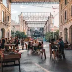 Cour intérieure de Darwin écosystème à Bordeaux avec des visiteurs assis à des tables, entourée de bâtiments en pierre aux arcades, avec structures métalliques et grues de construction visibles