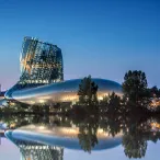 La Cité du Vin à Bordeaux, bâtiment architectural moderne avec façade inclinée illuminée, reflet dans l'eau calme au crépuscule