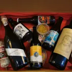 Coffret cadeau de dégustation de vins de Bordeaux contenant plusieurs bouteilles, un saucisson Levoni, des conserves et des accessoires gastronomiques dans une boîte jaune et rouge.
