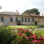 Bâtiment architectural de style néoclassique à Bordeaux, avec façade en pierre beige, colonnes blanches et roses rouges en parterre