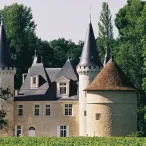 Château médiéval avec tours pointues et toits coniques, entouré de verdure près de Bordeaux