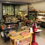 Intérieur d'une boutique bordelaise spécialisée dans les produits gastronomiques et les alcools, avec étagères remplies de bouteilles, bocaux et produits artisanaux, comptoirs en bois et une décoration chaleureuse.