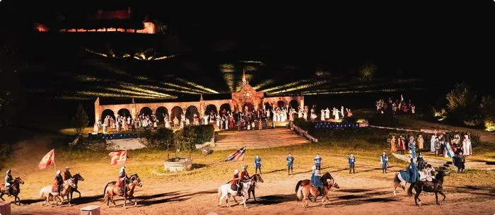 Spectacle nocturne de la Bataille de Castillon à Bordeaux avec cavaliers à cheval, public en arrière-plan et structures architecturales illuminées