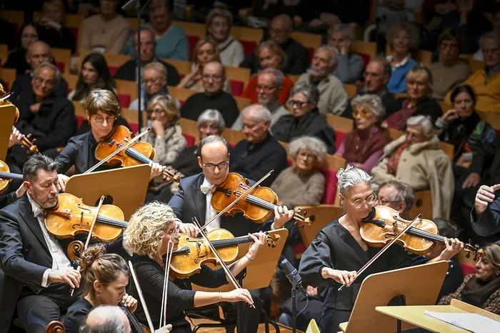 Orchestre symphonique en concert à Bordeaux interprétant la musique de John Williams, avec des violonistes au premier plan et un public attentif en arrière-plan.