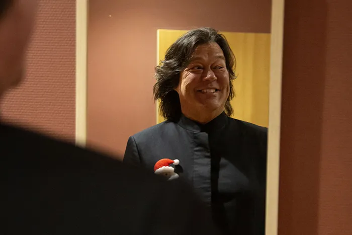 Une femme souriante en veste noire avec un badge de Père Noël rouge et blanc lors du Concert de Noël Radio Classique à Bordeaux