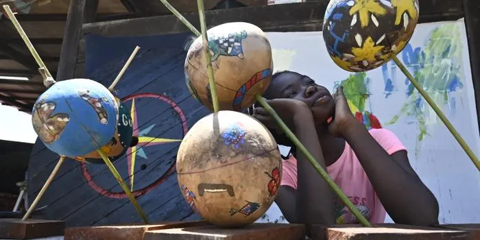 Une jeune fille observant des globes terrestres colorés et décorés suspendus lors de l'exposition Un globe des mondes au musée d'Aquitaine à Bordeaux.