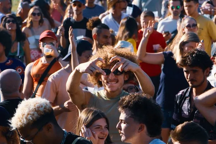 Foule joyeuse lors du festival Bordeaux Open Air au parc Treulon, avec une jeune femme au premier plan faisant un geste de cœur avec ses mains, entourée de spectateurs souriants.