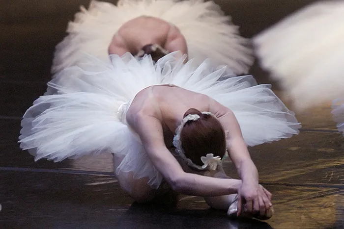Danseuse de ballet en tutu blanc exécutant une posture courbée sur scène lors d'une représentation du Lac des Cygnes à Bordeaux