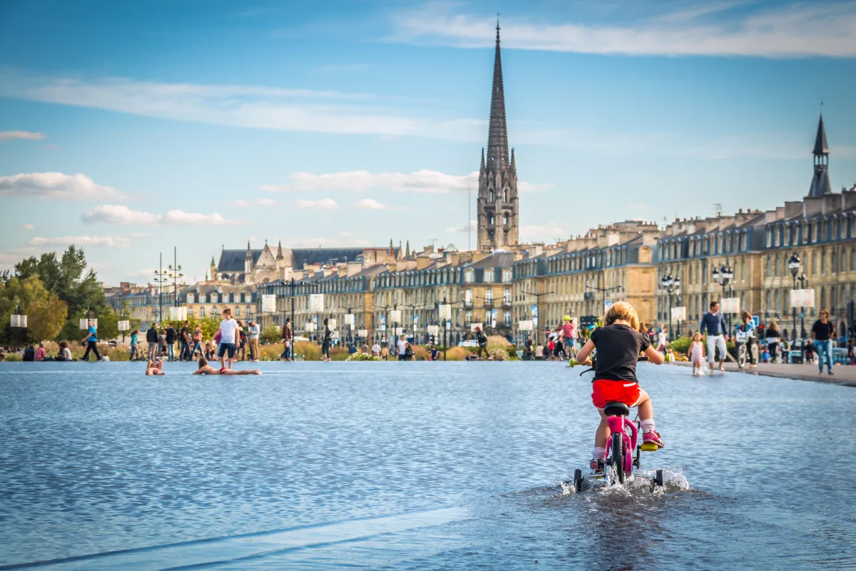 Cette photo met en avant une jeune fille en train de faire de vélo à roulettes sur le miroir d&#039;eau. 