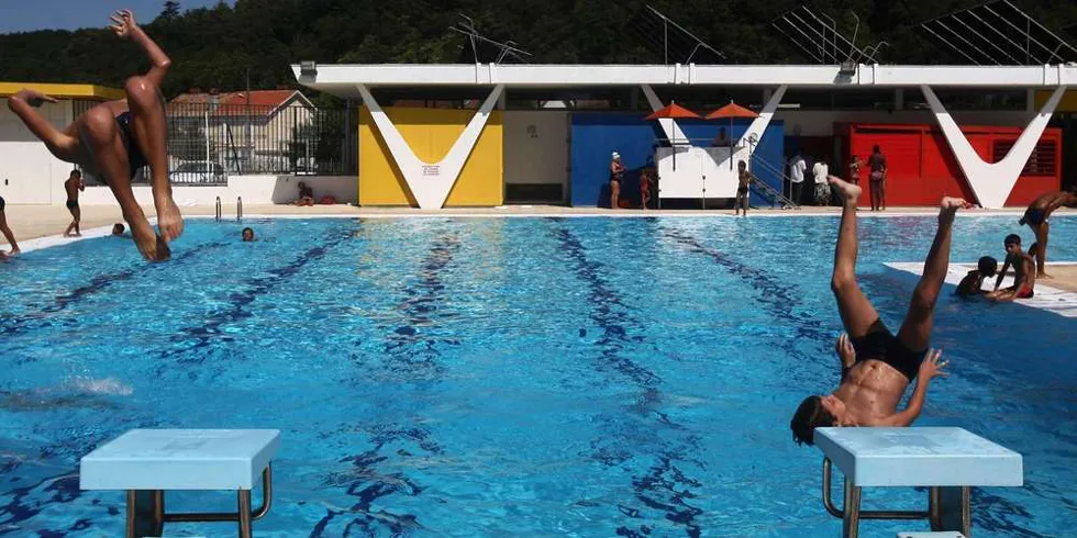 Piscine municipale de Floirac à Bordeaux avec nageurs et plongeurs dans le bassin, bâtiments colorés en arrière-plan