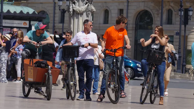 Groupe de cyclistes en visite guidée à Bordeaux, dont certains à vélo cargo orange, devant un bâtiment historique avec spectateurs en arrière-plan.