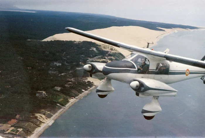 Vue aérienne depuis un avion de patrouille douanière survolant la côte atlantique avec dunes de sable et forêt littorale