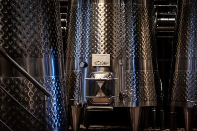 Cuves de fermentation en acier inoxydable avec motifs gauffrés au Château Yon-Figeac à Bordeaux, équipées de systèmes de contrôle de température.