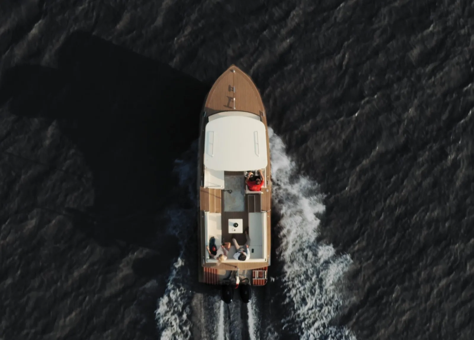 Vue aérienne du bateau-taxi Grattequina naviguant sur la Garonne à Bordeaux, avec ses vagues blanches caractéristiques de part et d'autre de la coque.