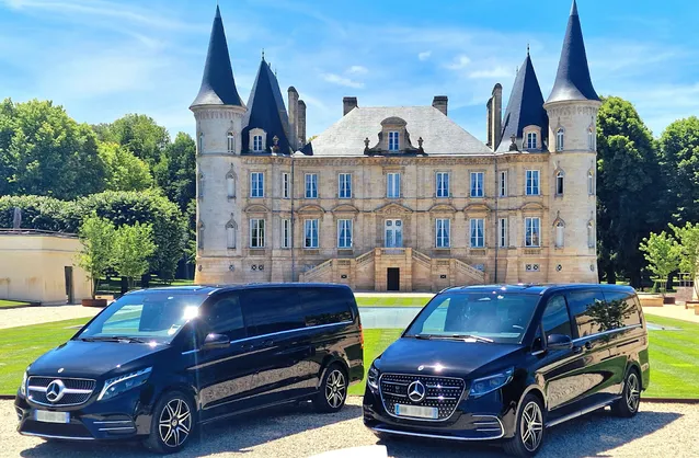 Deux minibus Mercedes noirs stationnés devant un château bordelais de style néo-gothique avec tours et pavillons, service de transport haut de gamme.