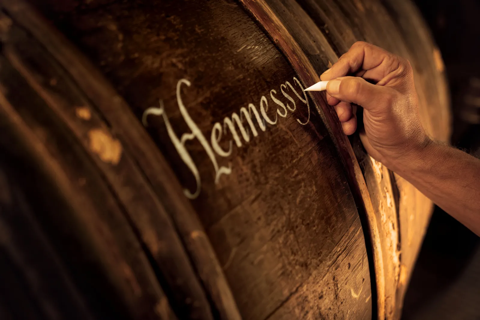 Main gravant le nom Hennessy sur un fût de cognac dans les caves de la maison Hennessy à Bordeaux