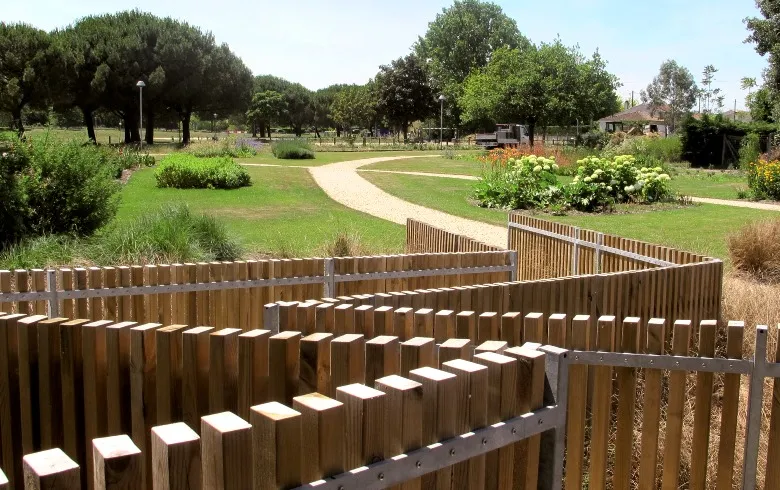 Parc aménagé des Bords de Jalle de Gajac à Bordeaux avec clôture en bois, allée sinueuse, pelouse verte, arbres et jardins fleuris
