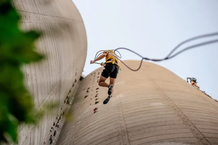 Grimpeur en équipement de sécurité escaladant la paroi externe d'une structure architecturale à Bordeaux lors de l'événement Vertigina 2026