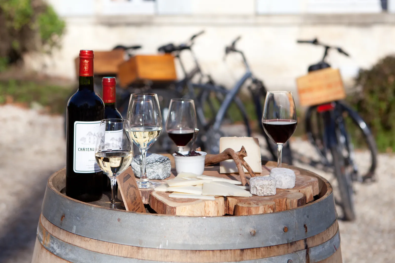 Dégustation de vins et fromages sur un tonneau en bois avec des vélos en arrière-plan dans une cour à Bordeaux