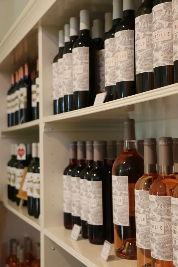 Étagères blanches présentant une collection de bouteilles de vin du Château Lestrille à Bordeaux, incluant des rouges et des rosés avec leurs étiquettes caractéristiques.