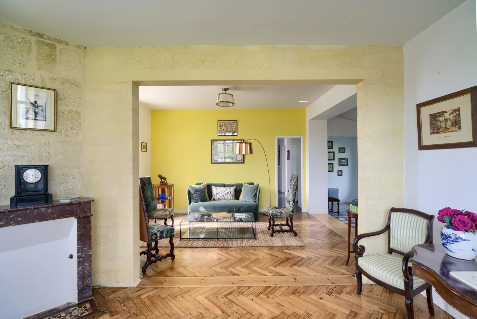 Intérieur élégant d'un salon avec murs jaunes vifs, parquet en chevrons, mobilier classique et accès à plusieurs pièces, situé à la Bastide de Siran à Bordeaux.