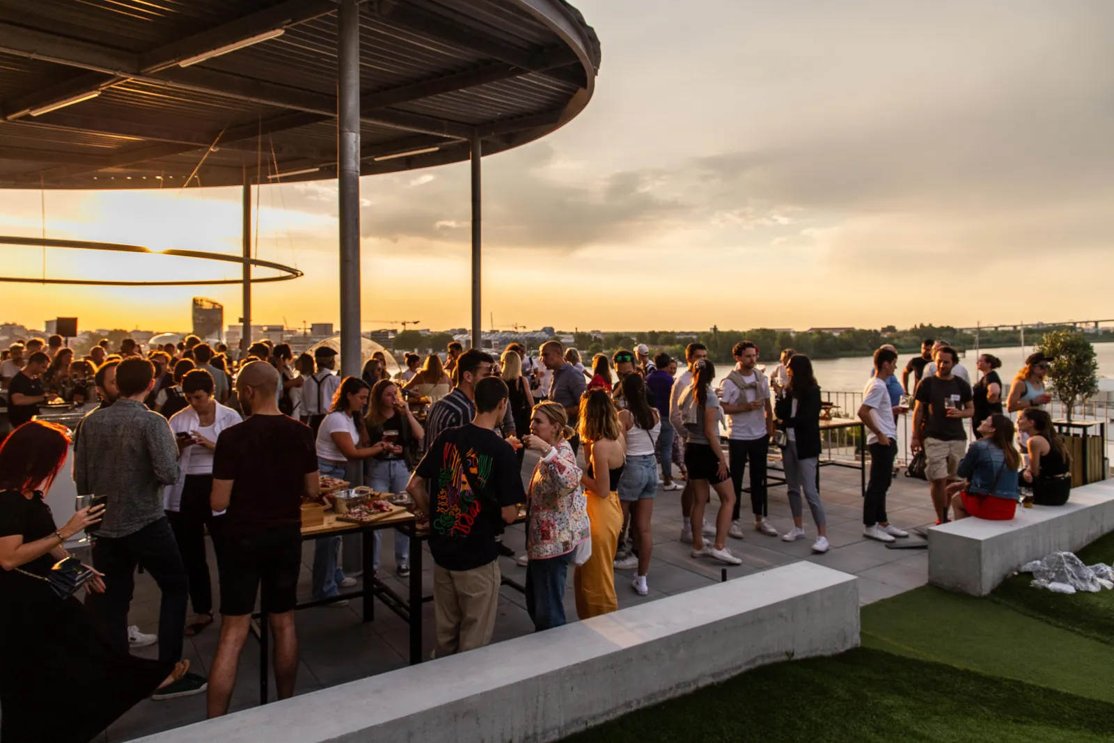 Foule de personnes lors d'un événement social en terrasse avec vue sur la Garonne à Bordeaux, au coucher du soleil, à la UCPA Sport Station.