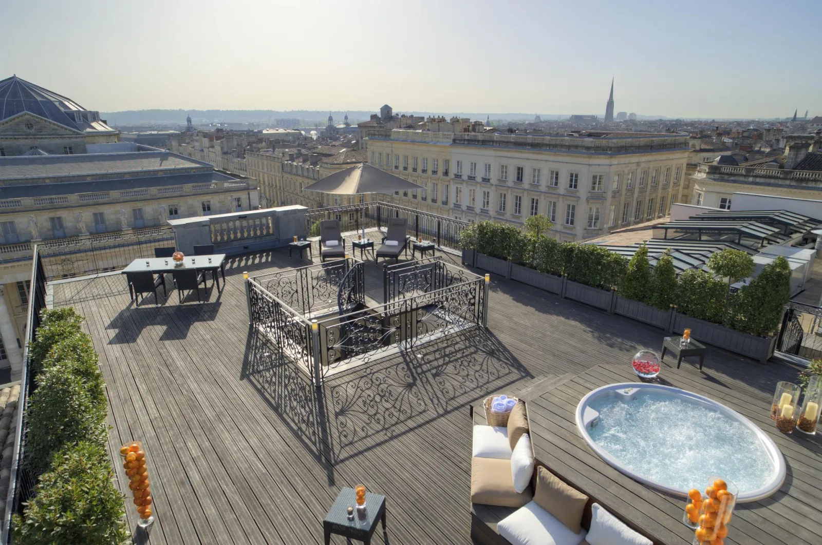Terrasse panoramique d'un hôtel de luxe à Bordeaux avec jacuzzi, mobilier de détente, vue sur la ville et l'architecture classique bordelaise