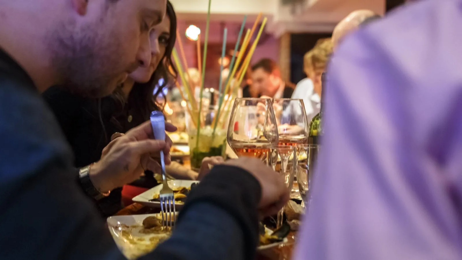 Convives dînant à une table décorée avec des verres de vin et des fleurs, lors d'un événement gastronomique à Bordeaux.