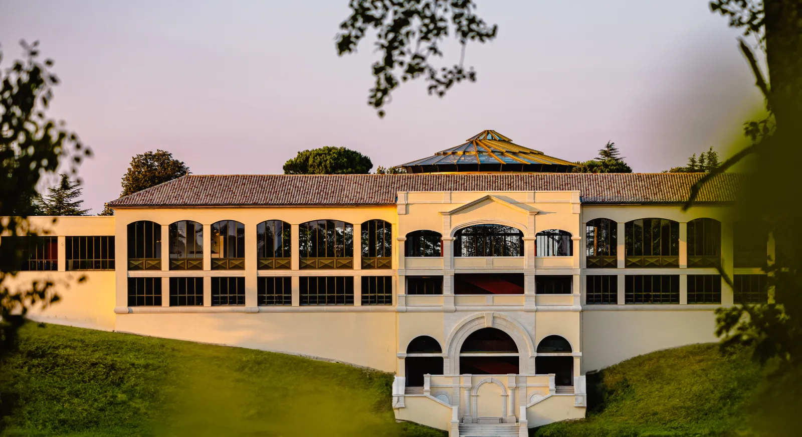 Château Plain Point à Bordeaux, bâtiment architectural classique avec façade jaune pâle, grandes fenêtres cintrées, toit en tuiles et dôme central, entouré de jardins et de verdure.
