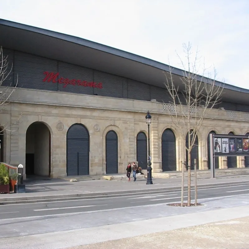Façade du cinéma Mégarama Bordeaux Bastide avec architecture moderne, grandes portes cintrées noires et enseigne rouge, situé à Bordeaux