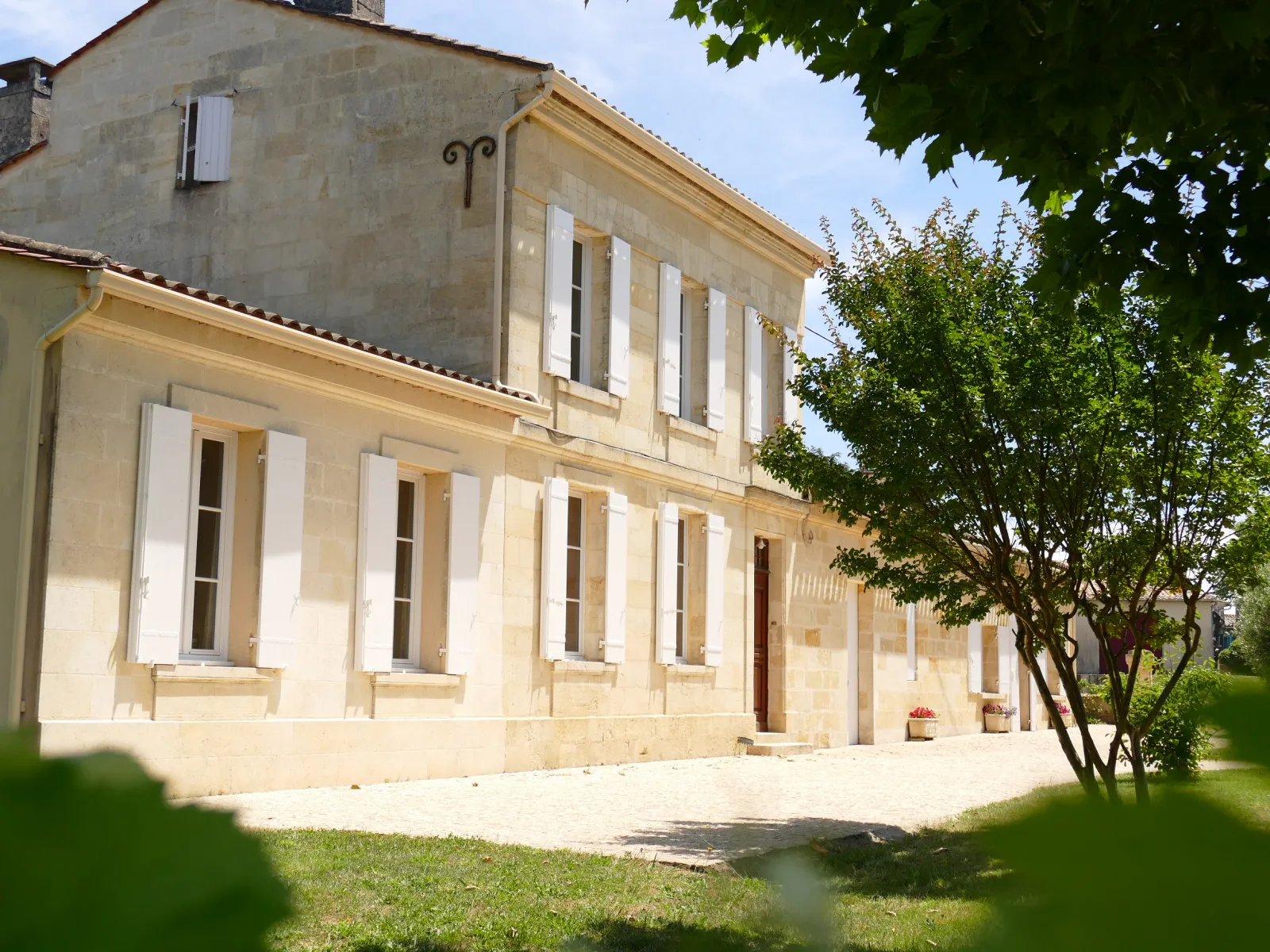 Façade du Château Laniote à Bordeaux, bâtiment en pierre de taille beige avec volets blancs, fenêtres symétriques et étage supérieur en retrait, entouré de verdure