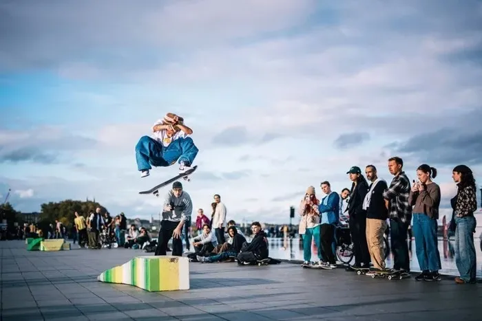 Un skateur effectue un saut acrobatique au-dessus d'un obstacle coloré lors du festival Connect à Bordeaux, devant une foule de spectateurs