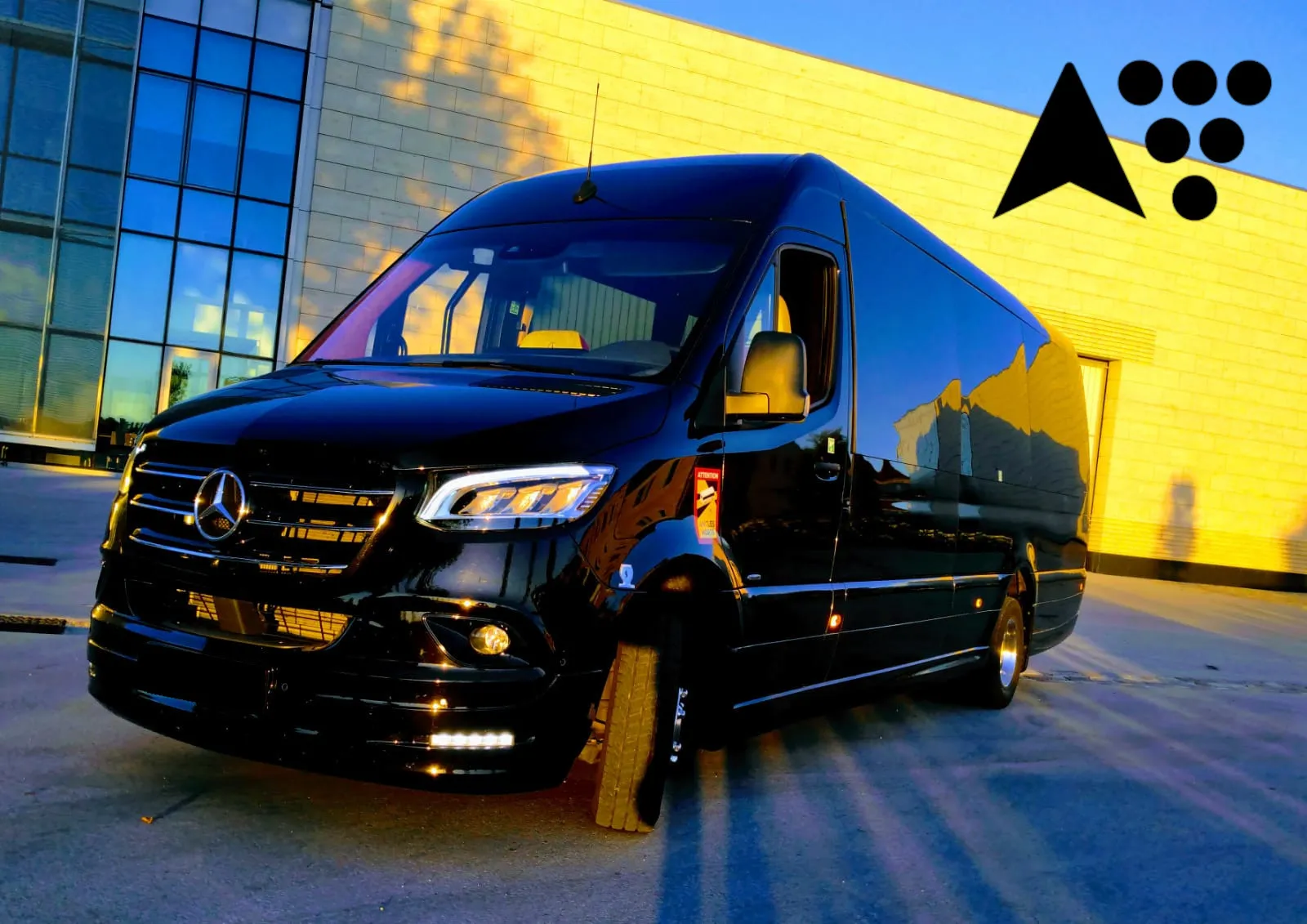 Un autocar Mercedes-Benz noir de BTA (Bordeaux Tourisme Affaires) stationné devant un bâtiment moderne à façade jaune et vitrée, en fin d'après-midi à Bordeaux.