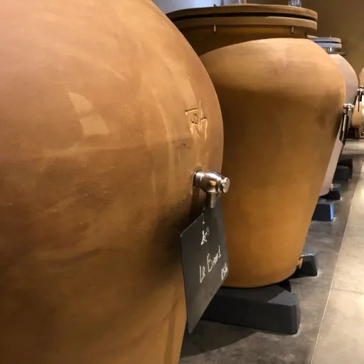 Rangée de fûts de chêne brun clair alignés dans une cave de vinification, avec des robinets de soutirage visibles, au Château Larmande à Bordeaux