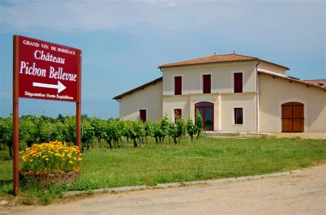 Panneau d'entrée du Château Pichon Bellevue, grand vin de Bordeaux, avec le bâtiment principal en arrière-plan entouré de vignobles