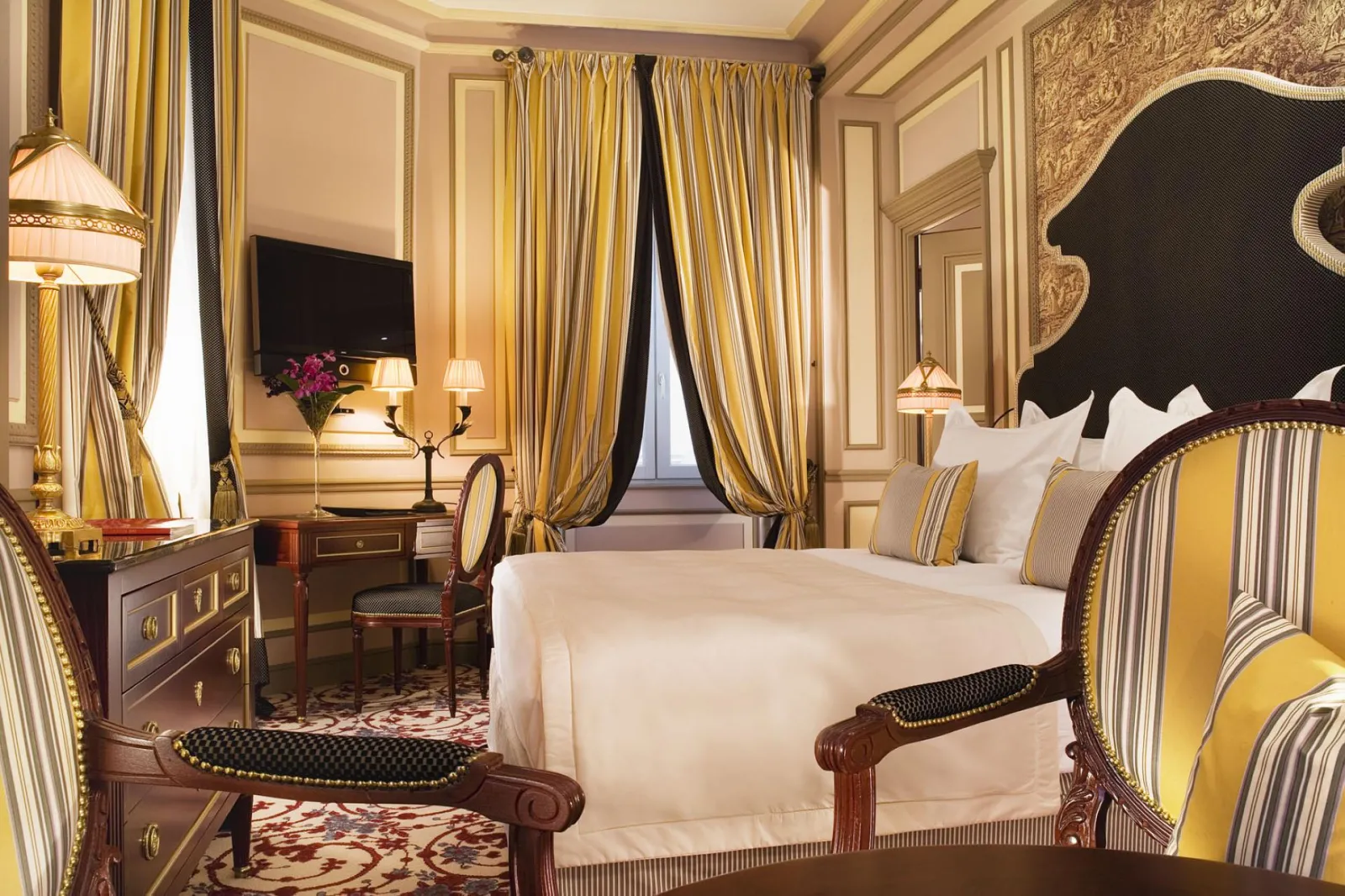 Chambre élégante de l'Intercontinental Grand Hôtel de Bordeaux avec lit king-size, décoration jaune et noir, rideaux à rayures, mobilier classique et vue sur la ville.