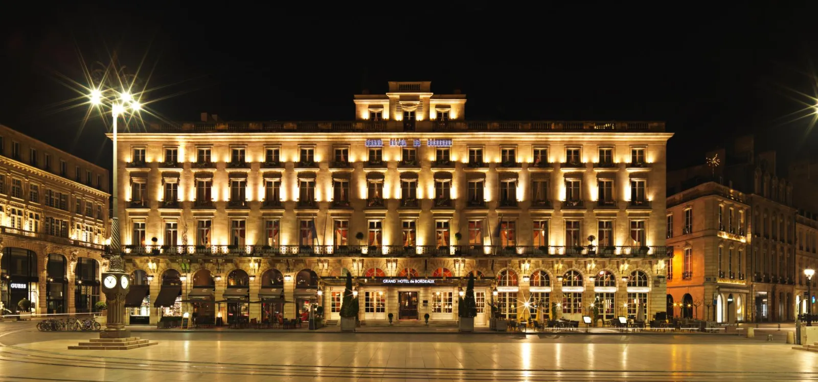 Façade illuminée de nuit du Grand Hôtel de Bordeaux, édifice historique aux lignes classiques avec colonnade et balcons, situé sur la Place de la Comédie à Bordeaux.