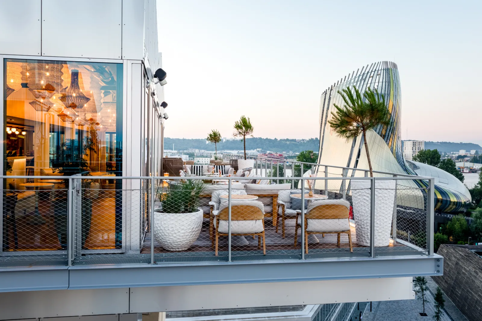 Terrasse panoramique d'un restaurant moderne à Bordeaux avec vue sur la ville, mobilier design et architecture contemporaine en verre et acier.