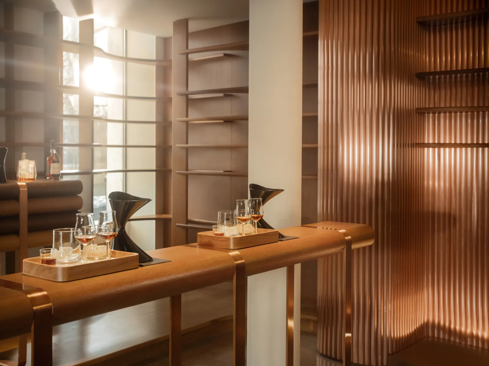 Espace de dégustation élégant de Hennessy à Bordeaux avec comptoir en bois, verres de cognac, mobilier moderne et grandes fenêtres avec volets en bois ajouré.