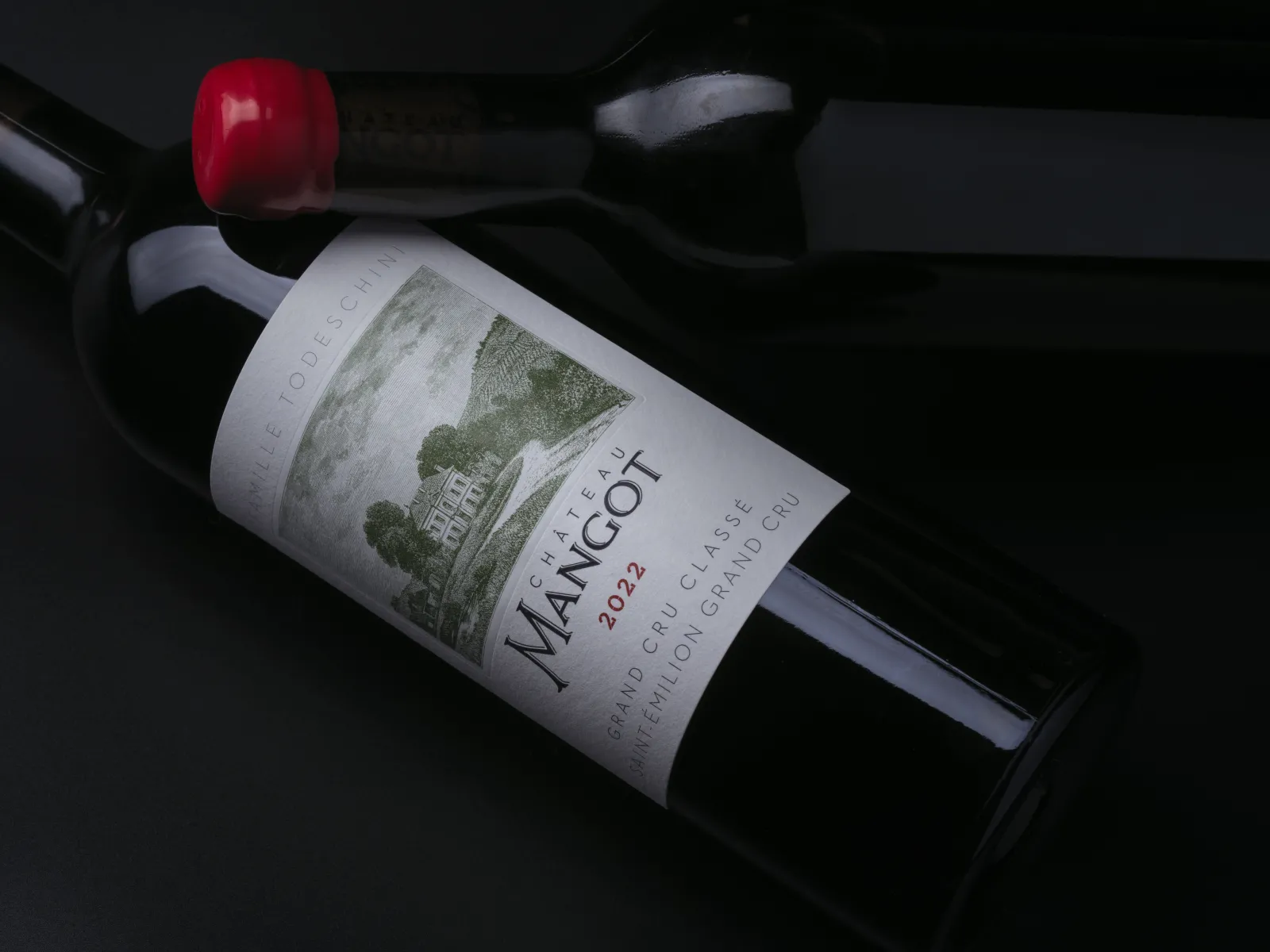 Bouteille de vin rouge Château Mangot 2022, grand cru de Bordeaux, posée sur un fond noir avec un bouchon de liège rouge visible