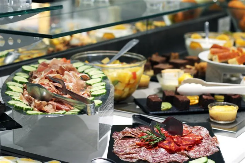 Plateau de charcuteries et mets délicats avec jambon cru, salami, concombre, légumes et accompagnements variés exposés dans une vitrine de delicatessen à Bordeaux