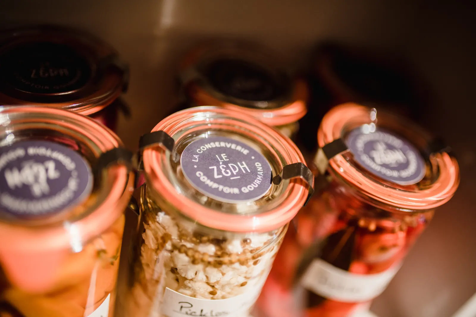 Bocaux en verre avec couvercles orange et étiquettes bleues contenant des céréales et produits conservés, marque Le Zeph de Bordeaux
